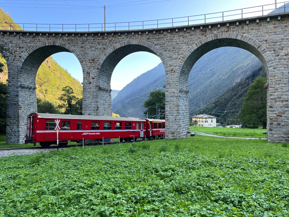 Bernina Express red train passing through the arches of the Brusio circular viaduct